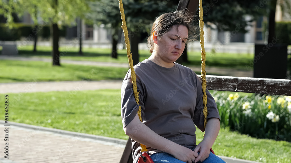 Adult woman riding rope swing sits with upset and furious expression in park illuminated with