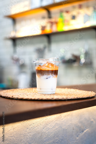 An ice milk coffee in plastic cup and served on counter bar. Drink and beverage object photo.