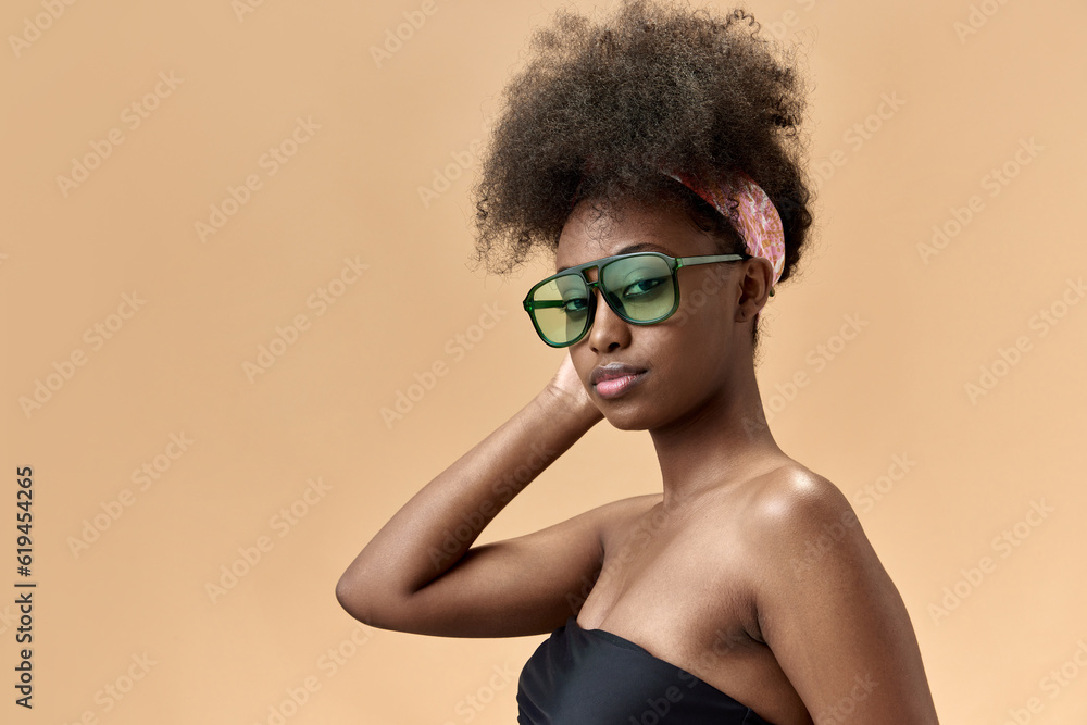 Portrait of young, stylish, beautiful, african woman in tredy sunglasses, top posing against studio background Portrait of young, stylish, beautiful, african woman in tredy sunglasses, top posing against studio background