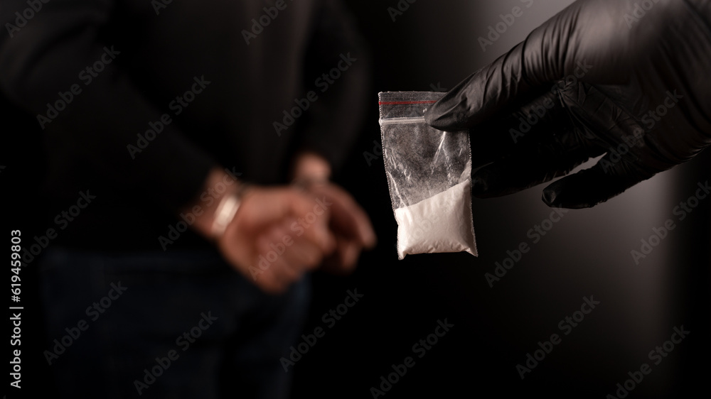 Polizeikurier für Drogenhaftungen. festgenommener Händler hält eine kleine Tüte Kokain in der Hand.