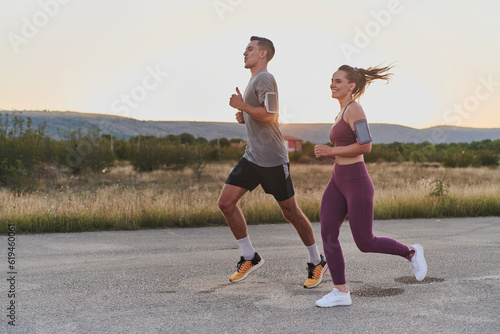 A handsome young couple running together during the early morning hours, with the mesmerizing sunrise casting a warm glow, symbolizing their shared love and vitality