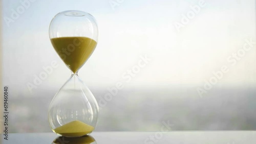 hourglass on table, sand flowing through the bulb of sandglass, time is money concept, times passing concept like work or business deadline, resemble urgency running out of occasion in life photo