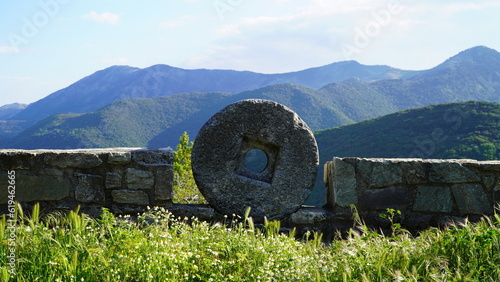 Foto Round stone millstones on the background of green hills in Greece