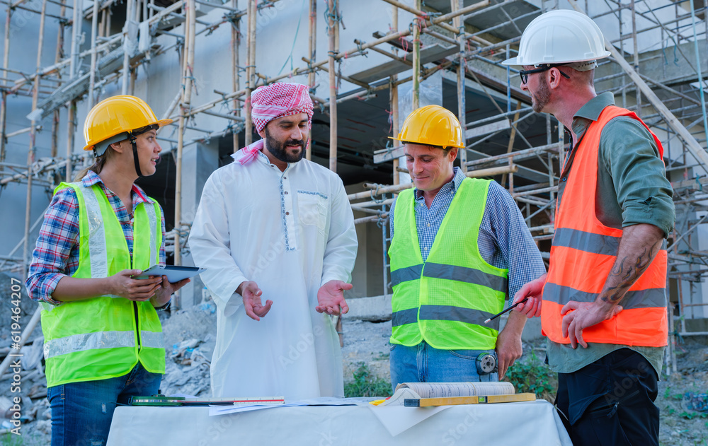 Multi-ethnic engineer in protective suit and entrepreneur studying and inspecting the construction work on site. Cooperation concept. Multi-ethnic engineer in protective suit and entrepreneur studying and inspecting the construction work on site. Cooperation concept.