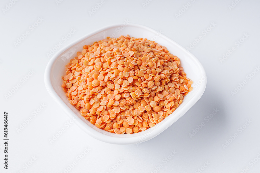 dried orange lentil flakes in a white plate on a white background dried orange lentil flakes in a white plate on a white background