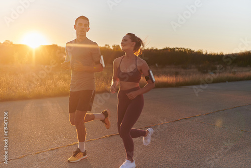 Fototapeta Naklejka Na Ścianę i Meble -  A handsome young couple running together during the early morning hours, with the mesmerizing sunrise casting a warm glow, symbolizing their shared love and vitality