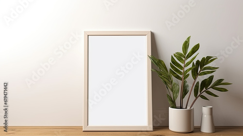 A blank photo frame mockup placed on a wooden floor in an empty room, surrounded by a lush green plant