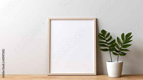 A blank photo frame mockup placed on a wooden floor in an empty room, surrounded by a lush green plant