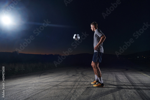 Portrait of a young handsome soccer player man on a street playing with a football ball © .shock