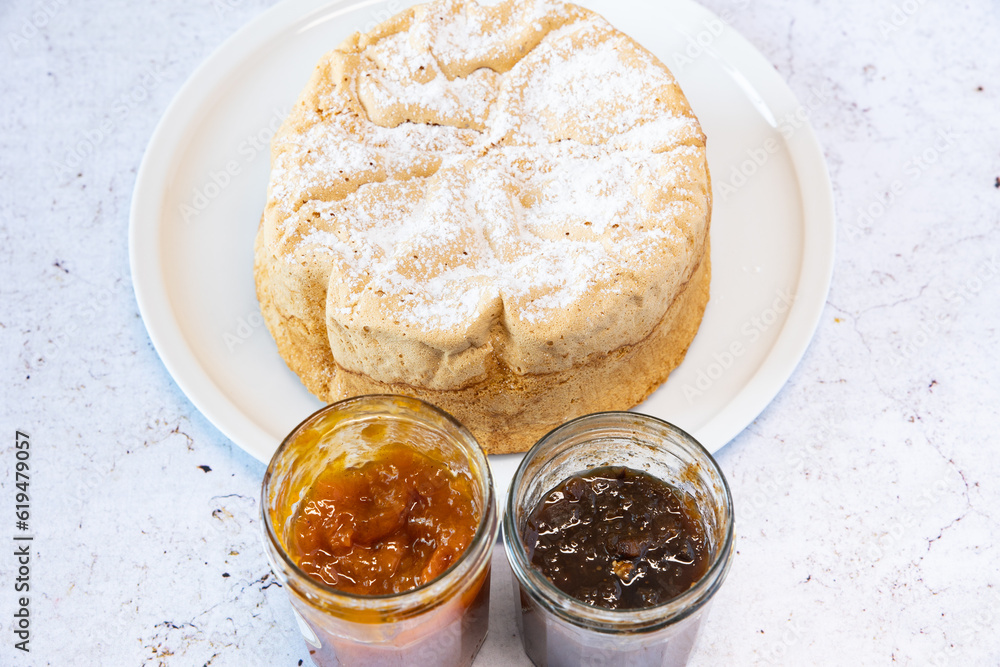 Homemade Savoie cake on a pretty white porcelain dish with jam in a jar Homemade Savoie cake on a pretty white porcelain dish with jam in a jar