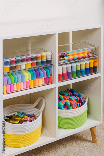 White shelving with various material for creativity and kids art activity. Stationery and supplies for drawing and craft. Organizing and storage in craft room.