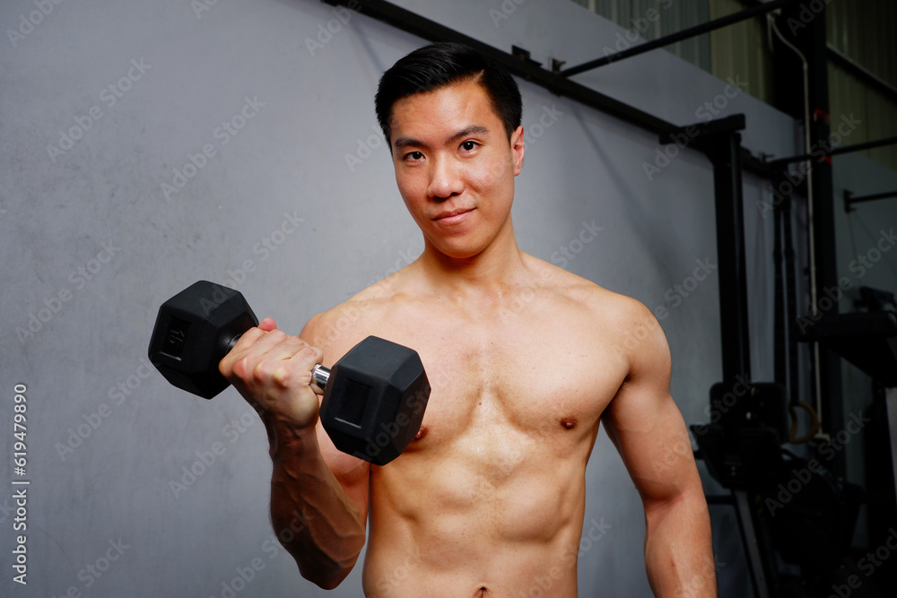 young man lifting dumbbells exercising in the gym fitness concept.