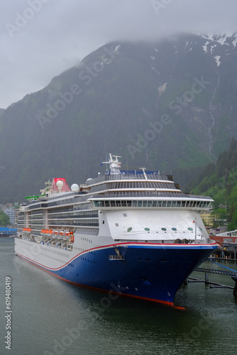 Modern cruiseship cruise ship liner Spirit docked at terminal in Juneau, Alaska during heavy rain and low cloud nature scenery with mountains and foggy misty atmosphere