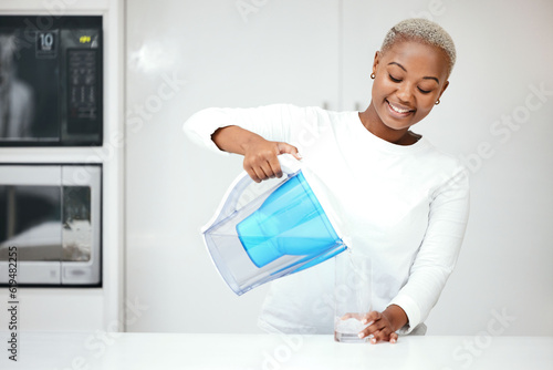 Water, filter and black woman with jug in kitchen to refresh with glass, liquid and cold hydration. Happy, thirsty and female person pouring pure aqua beverage from pitcher for clean drinking at home