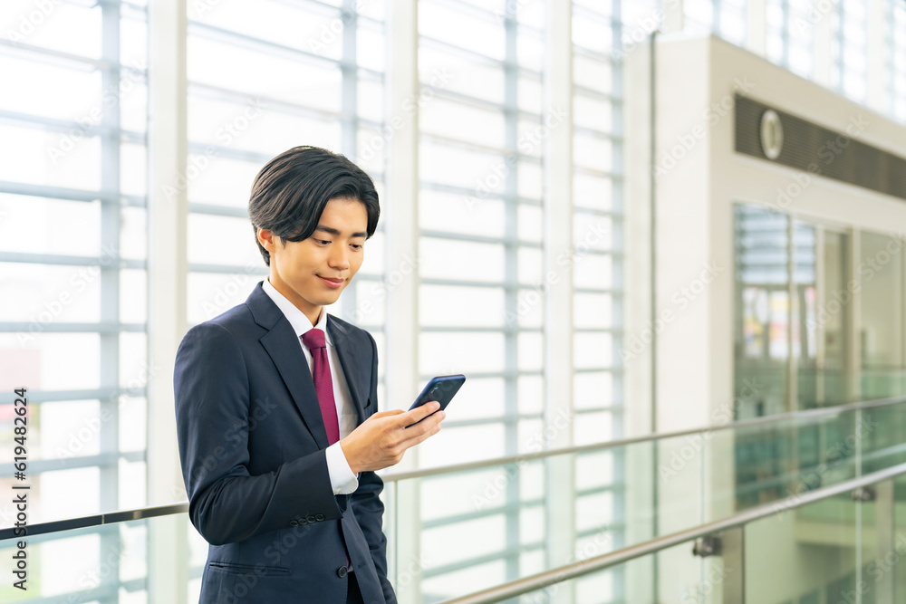 ロビーでスマホを使う若いビジネスマン ロビーでスマホを使う若いビジネスマン