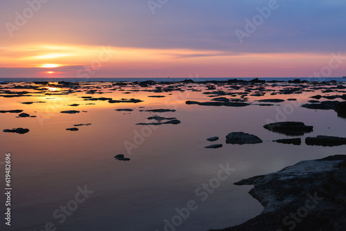 Sunset Reflected on the Sea as in a Mirror with Rocks Emerging on the Surface of the Water © GioRez