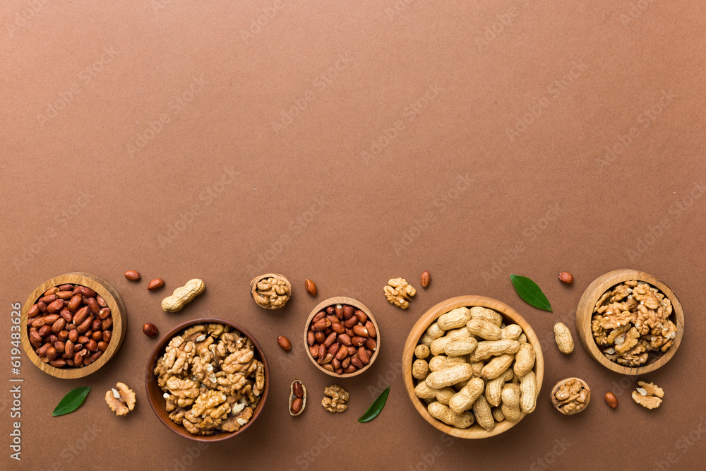 Walnut kernel halves with peanut, in a wooden bowl. Close-up, from above on colored background. Healthy eating groundnut concept. Super foods with copy space Walnut kernel halves with peanut, in a wooden bowl. Close-up, from above on colored background. Healthy eating groundnut concept. Super foods with copy space