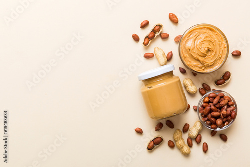 Foto Bowl of peanut butter and peanuts on table background