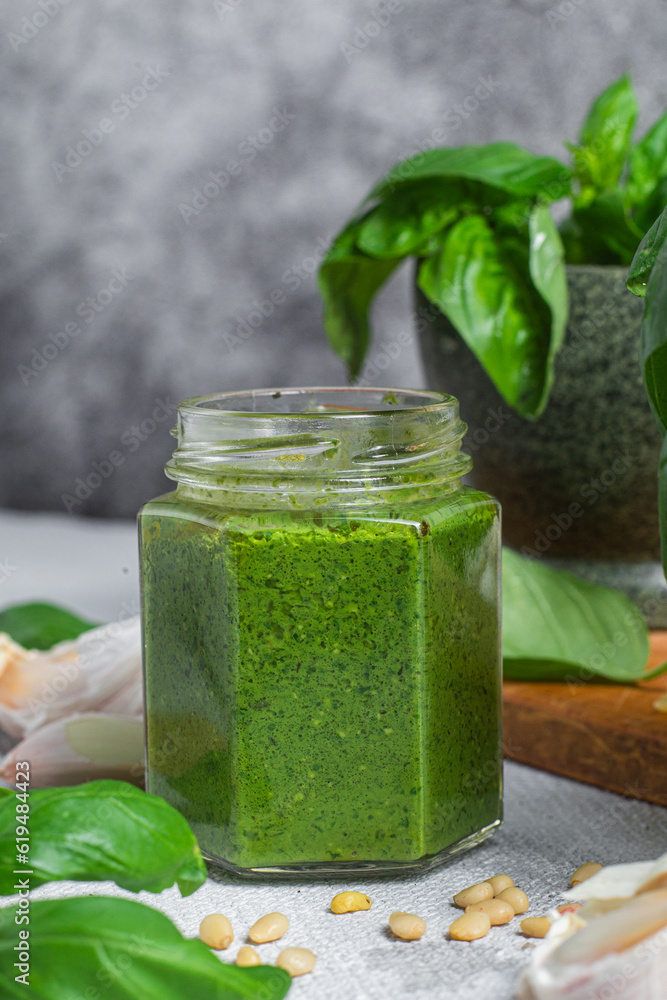 Pesto sauce in a glass jar on the table. Basil Pesto sauce in a glass jar on the table. Basil