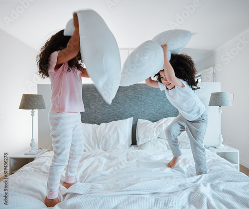 Fotografija Happy siblings, pillow fight and playing on bed in morning together for fun bonding at home
