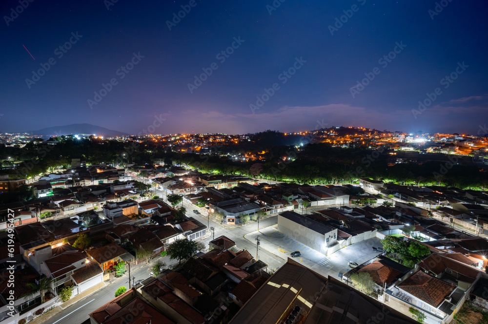 Fototapeta premium Dramatic night sky image of the city of Pedreira, in the interior of São Paulo. Mix of orange and purple colors with stars. Long exposure.