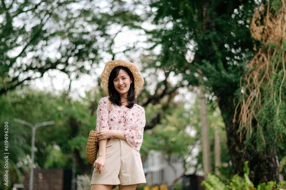 Portrait of asian young woman traveler with weaving hat and basket happy smile on green public park nature background. Journey trip lifestyle, world travel explorer or Asia summer tourism concept. Portrait of asian young woman traveler with weaving hat and basket happy smile on green public park nature background. Journey trip lifestyle, world travel explorer or Asia summer tourism concept.