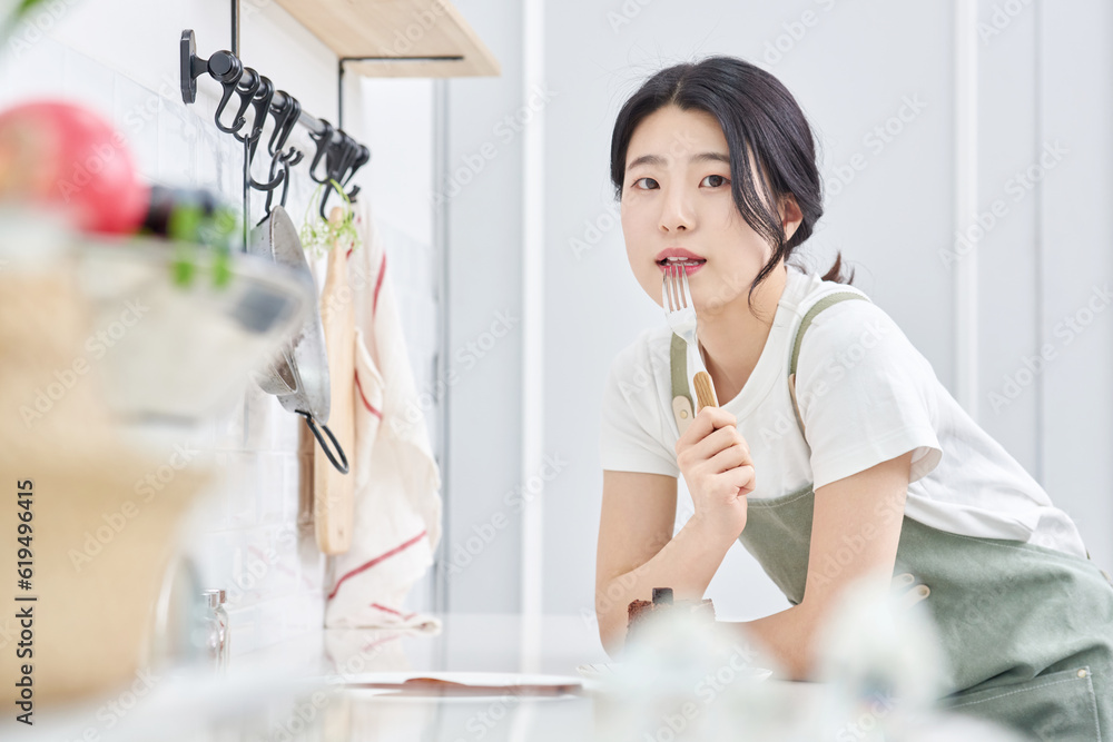 young Asian female model who makes a piece of cake in the kitchen and eats it deliciously young Asian female model who makes a piece of cake in the kitchen and eats it deliciously