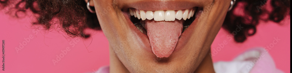 Young caribbean man with piercing showing his tongue at camera