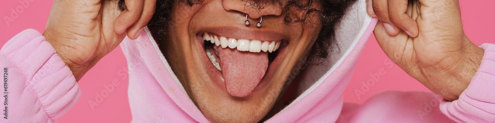 Obraz premium Young caribbean man with piercing showing his tongue at camera