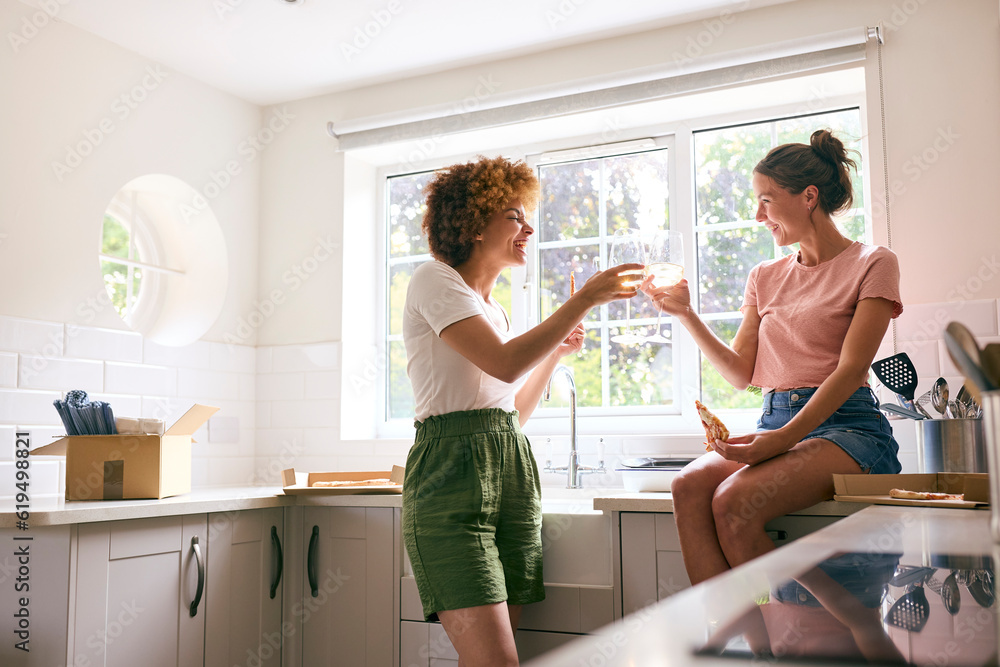 Fototapeta premium Two Female Friends Or Same Sex Couple Celebrating With Pizza And Wine On Moving Day In New Home