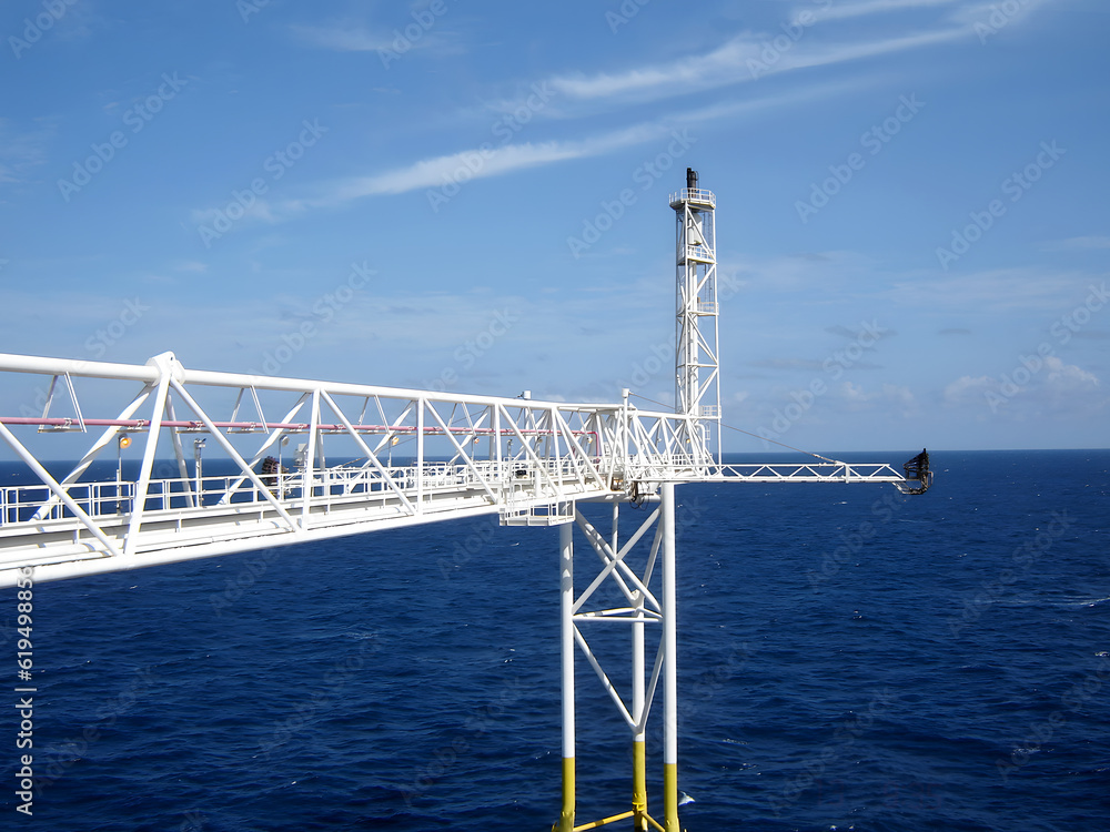 Offshore Flare stack of Gas Flare system on clouds in the blue sky background, after down gas process to 0% for the system preventive maintenance Offshore Flare stack of Gas Flare system on clouds in the blue sky background, after down gas process to 0% for the system preventive maintenance