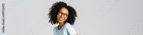 Black curly woman wearing eyeglasses smiling and looking aside