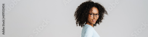 Black curly woman wearing eyeglasses smiling and looking at camera