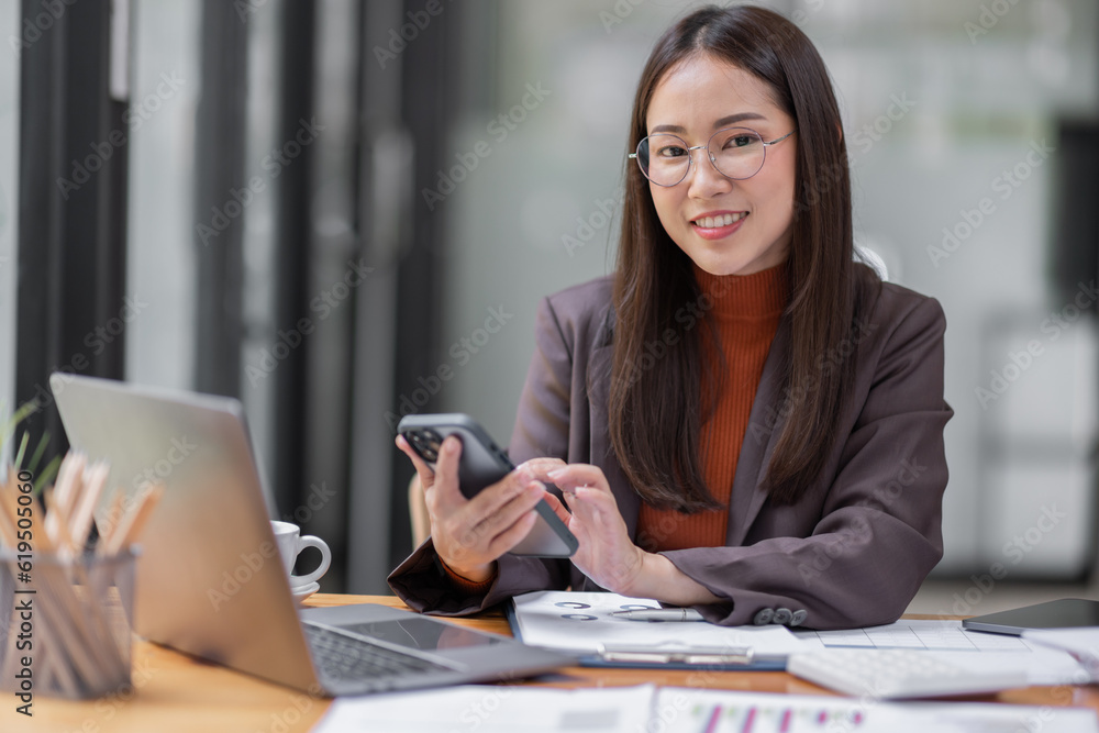 business Asian woman freelancer wear glasses is working her job on phone and laptop in the office. Doing accounting analysis report real estate investment data, Financial and tax systems concept. business Asian woman freelancer wear glasses is working her job on phone and laptop in the office. Doing accounting analysis report real estate investment data, Financial and tax systems concept.