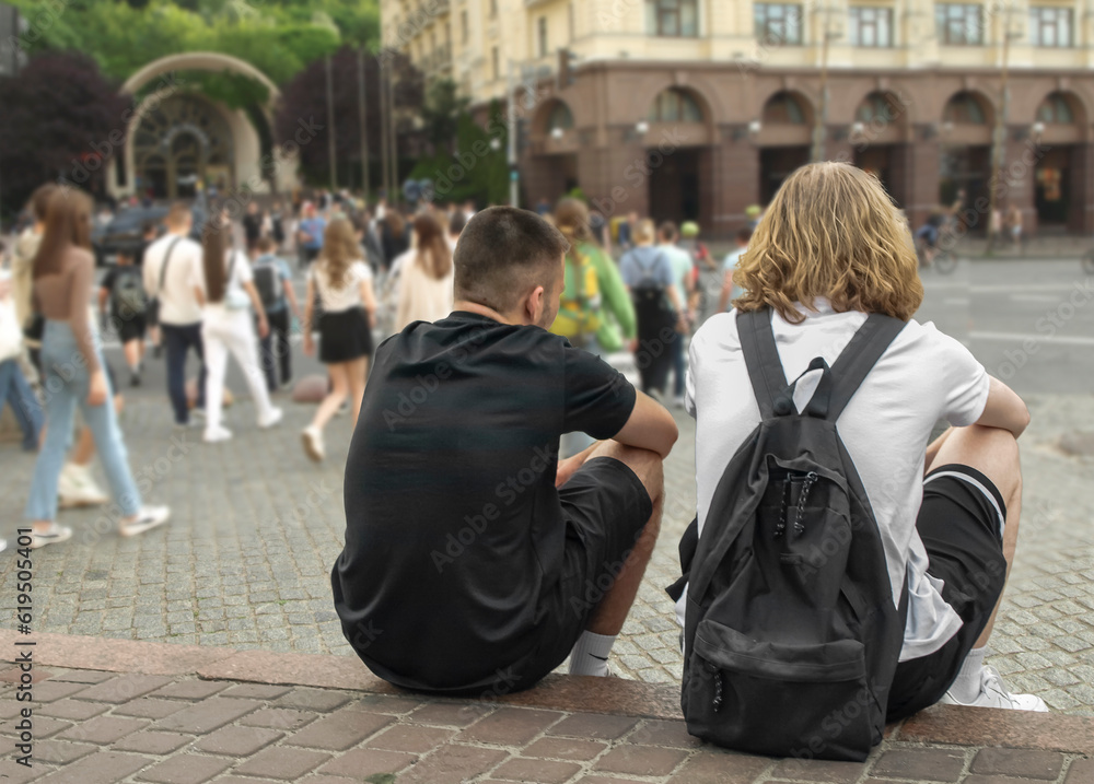 Obraz premium Young people sit on the edge of the sidewalk