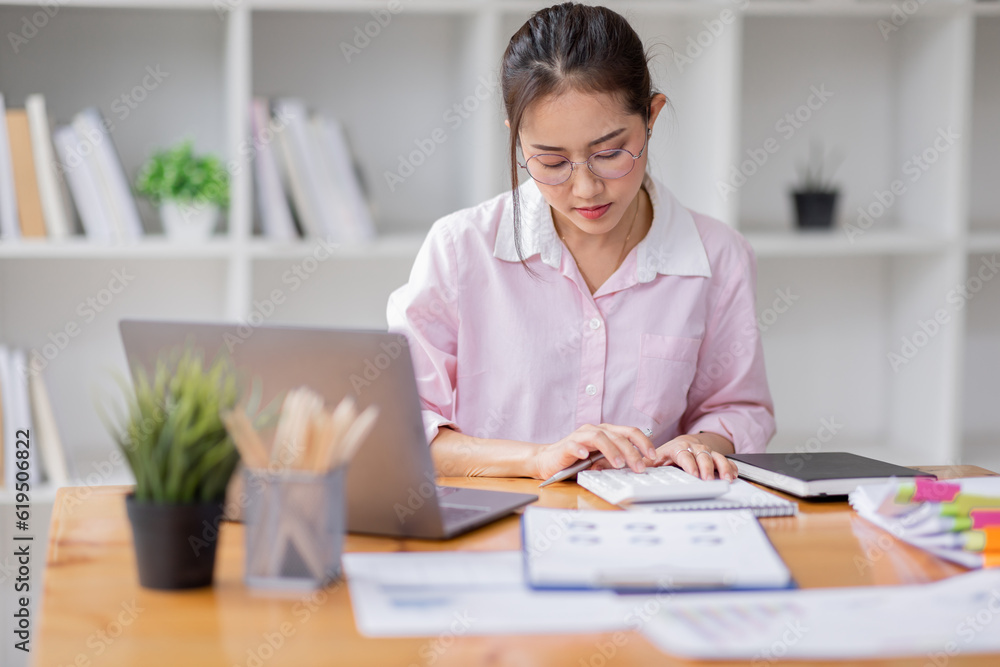 Asian business woman wear glasses or accountant working on calculator to calculate business data, accounting document and laptop computer at office, business concept Asian business woman wear glasses or accountant working on calculator to calculate business data, accounting document and laptop computer at office, business concept