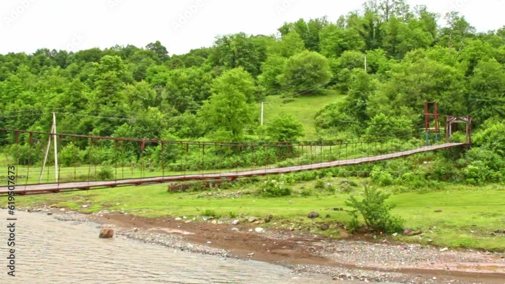 Suspension flyer rustic wooden bridge over mountain river, idyllic green nature Suspension flyer rustic wooden bridge over mountain river, idyllic green nature