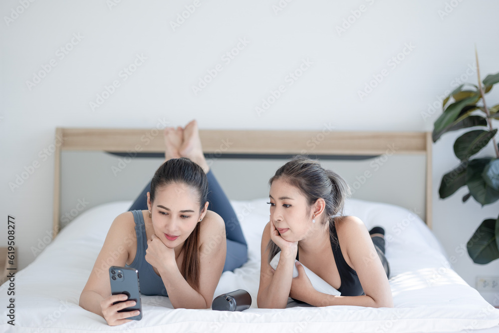 two asien women using smartphone on bed at home two asien women using smartphone on bed at home