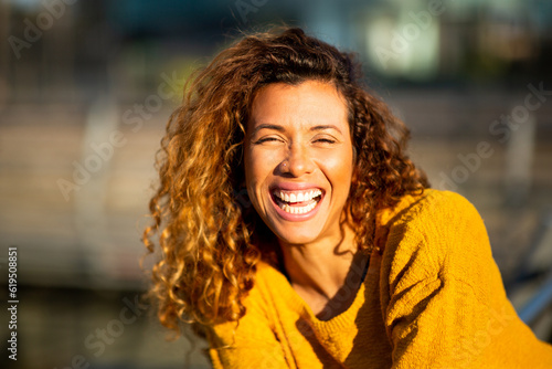 Laughing young hispanic woman looking at camera outside