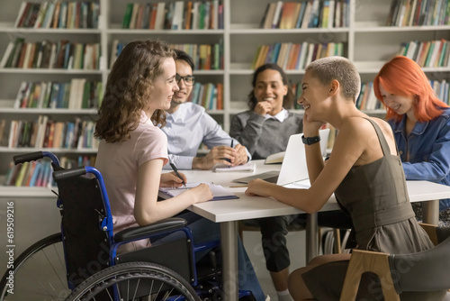 фотографія Young student girl with disability cooperating on class project in library with