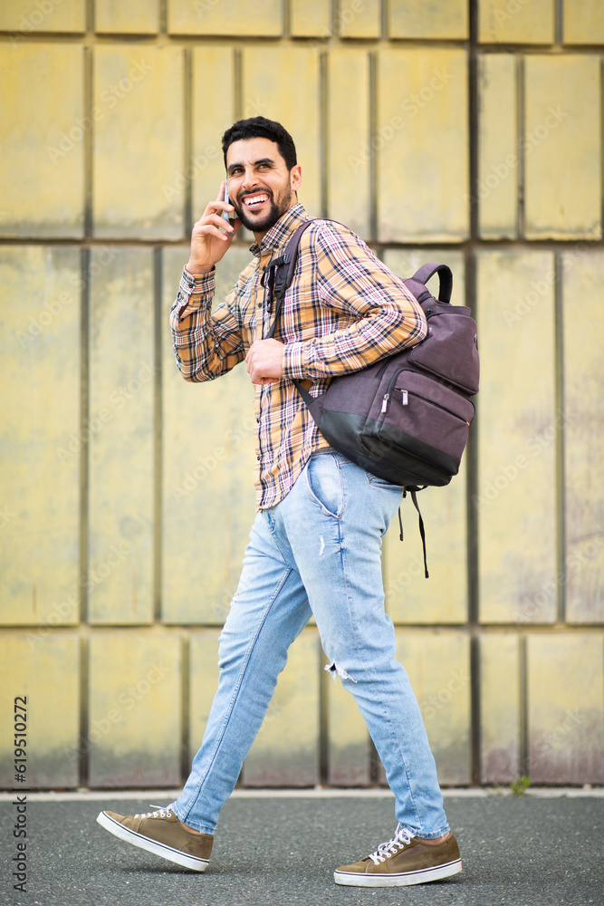 Cool young arabic man walking with bag and talking on phone Cool young arabic man walking with bag and talking on phone