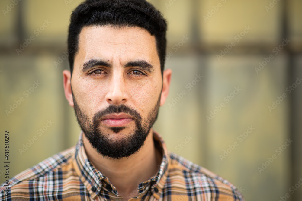 Serious looking arabic man wearing checkered pattern shirt Serious looking arabic man wearing checkered pattern shirt