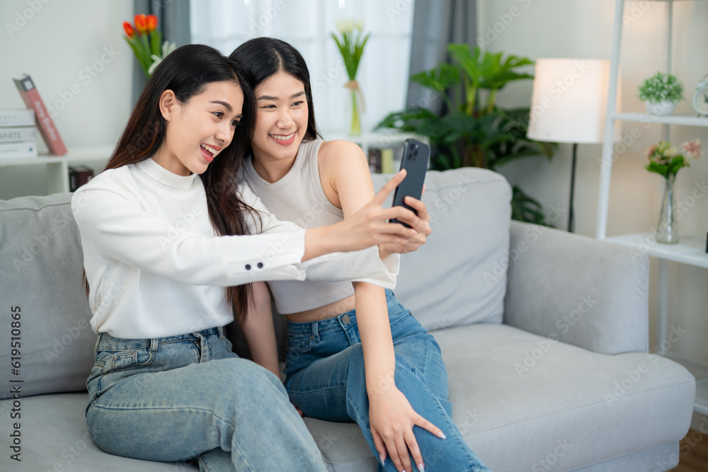 Asian couple taking selfies on vacation together in living room at home. Smiling female couple spending quality time together. Lesbian couple love moments happiness concept. Asian couple taking selfies on vacation together in living room at home. Smiling female couple spending quality time together. Lesbian couple love moments happiness concept.