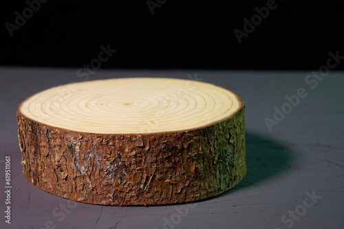 Beautiful wooden stand on a black background. Wooden decor on a concrete surface. Decorative log with bark.