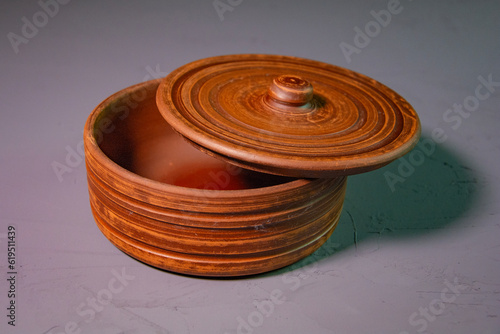 Brown empty clay pot with lid. Clay decor on a gray concrete surface. Decorative dishes of brown color.