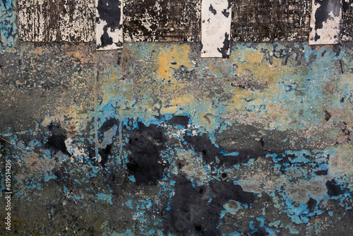 Old metallic panel with scraps of flaking paint layers, grunge background