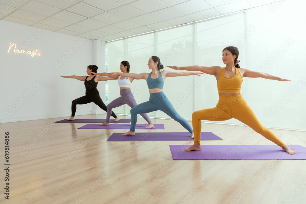 A group of women in yoga class doing the warrior pose