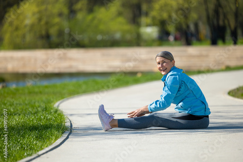 Woman sittingon the yoga mat in the park and doing stretching