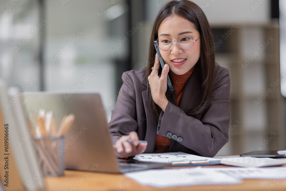 Cheerful business Asian woman freelancer wear glasses making telephone call share good news about project working in office workplace, business finance concept. Cheerful business Asian woman freelancer wear glasses making telephone call share good news about project working in office workplace, business finance concept.