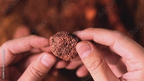 Man's hand holding a piece of copper to examine it for industrial use